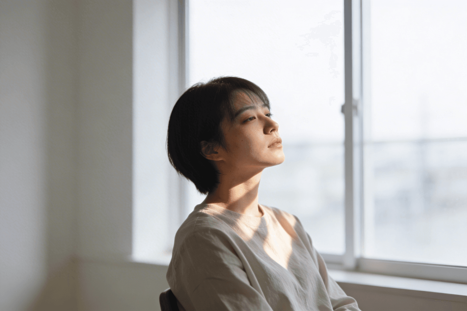 Portrait of a writer sitting by a window in soft morning light, eyes half closed